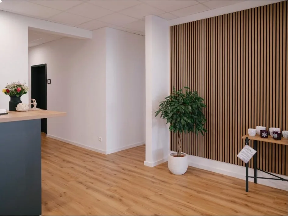 Heller Empfangsbereich mit Holzlamellen-Wand, Anmeldetheke und Pflanze