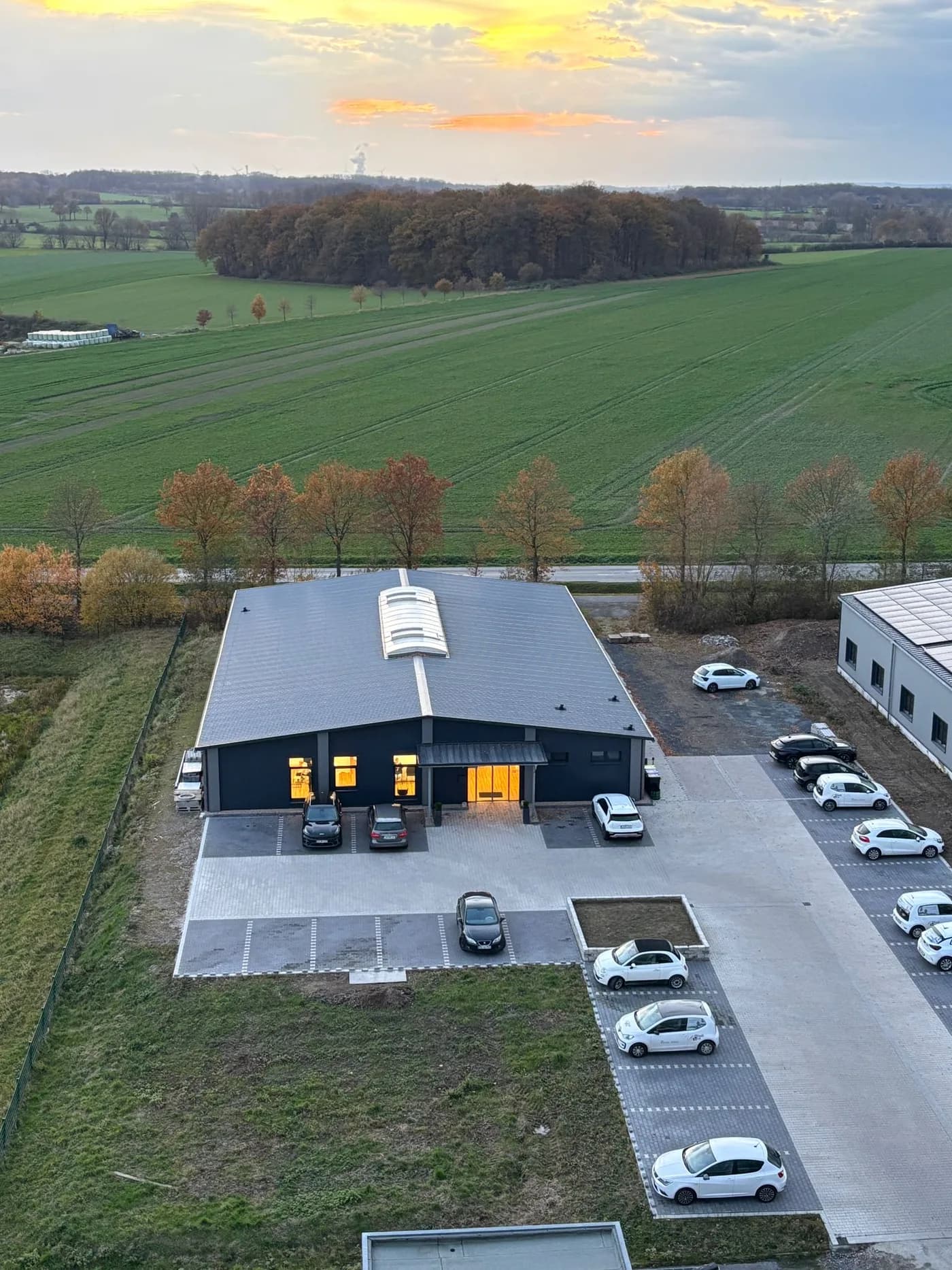 Luftaufnahme des Riedimed Trainings- und Therapiezentrums in Südkirchen mit Parkplatz und umliegenden Feldern bei Sonnenuntergang